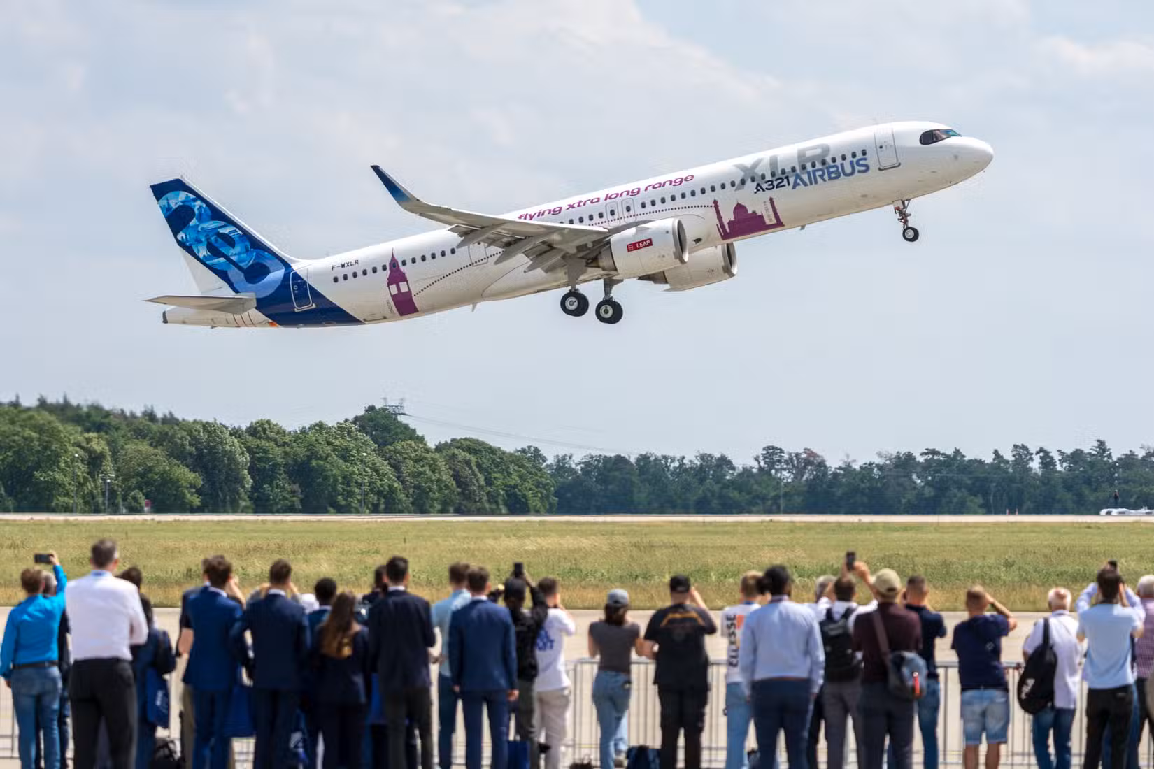 Airbus A321 XLR departing in front of a crowd at air show.