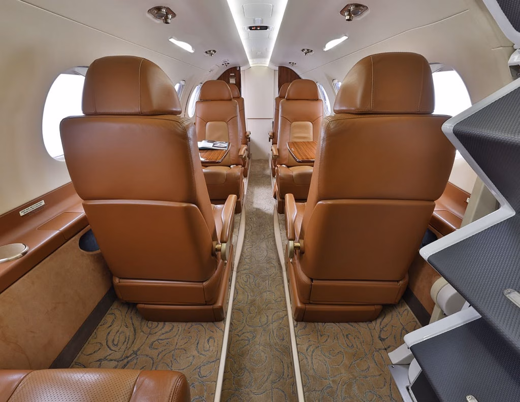 2015 Embraer Phenom 300 interior showing spacious club seating layout with tan leather seats and aisle view
