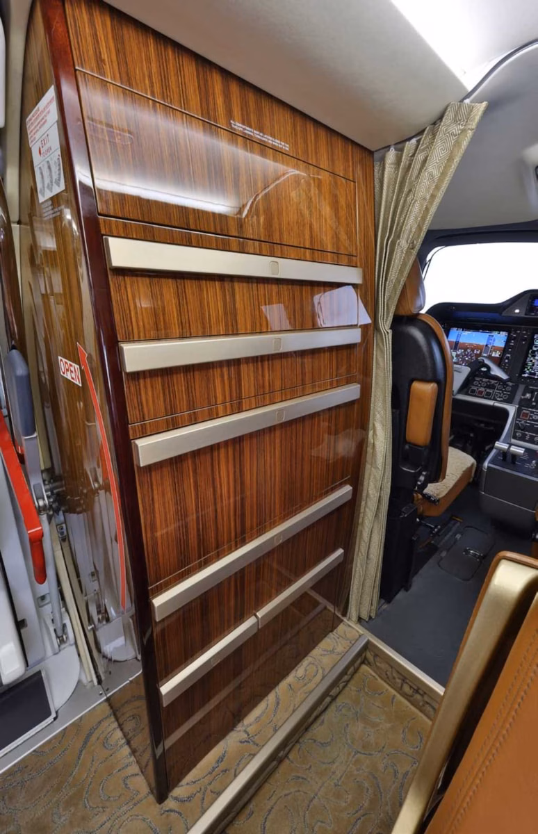 2015 Embraer Phenom 300 forward cabin storage cabinet and entry area with glossy wood veneer finish